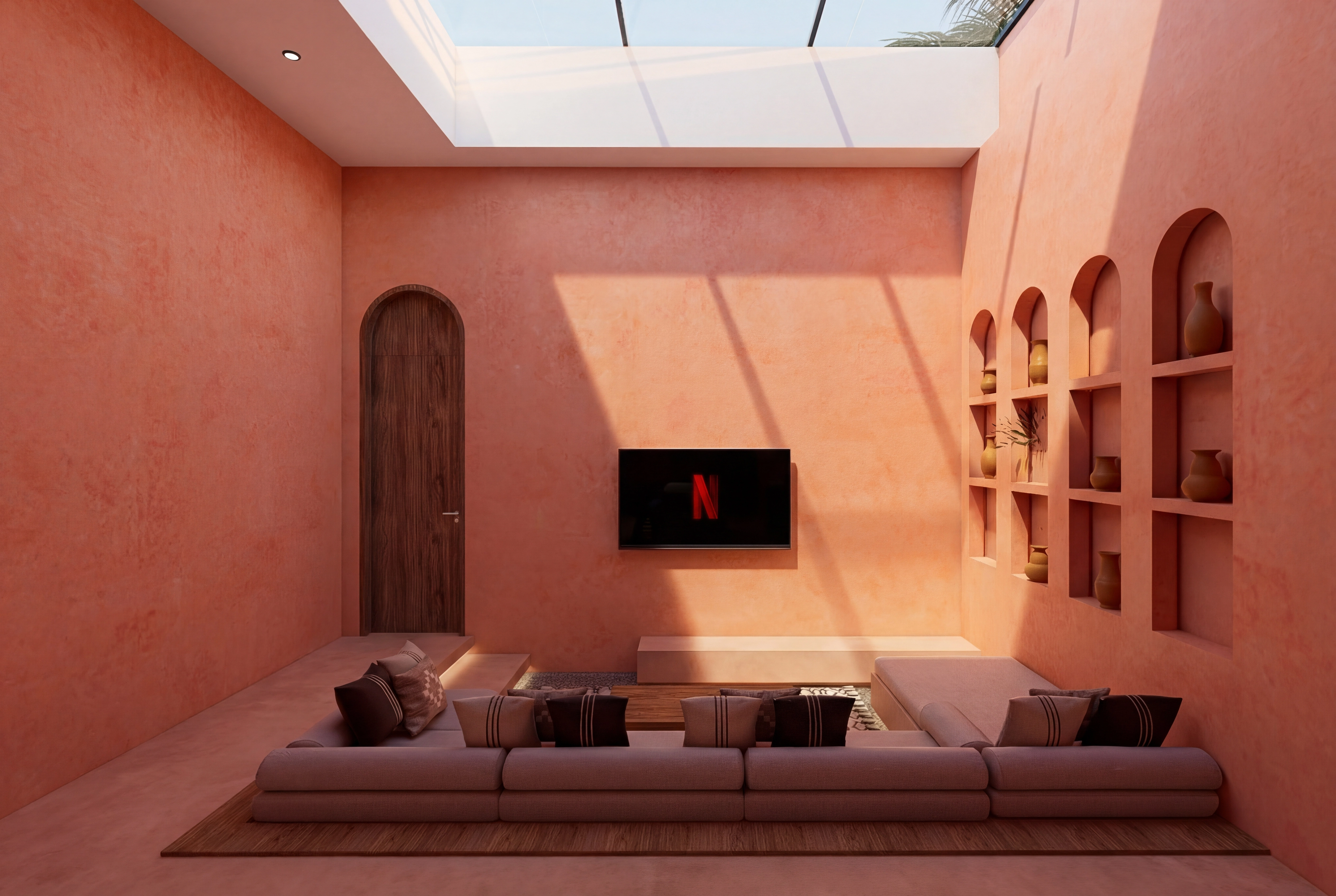 Wide view of the skylit sunken living room with a large sofa, wooden arched door, and wall-mounted TV
